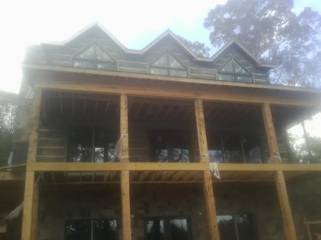 Dormers and porch framing on a large log home under construction — Roof Coating work by our crew in Mayville